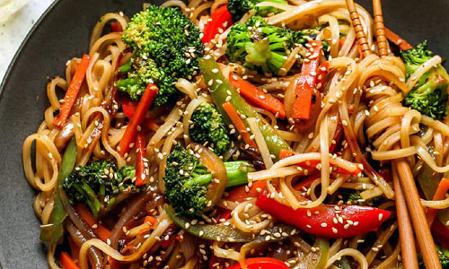 Stir fried wheat noodles with mixed green and orange vegetables